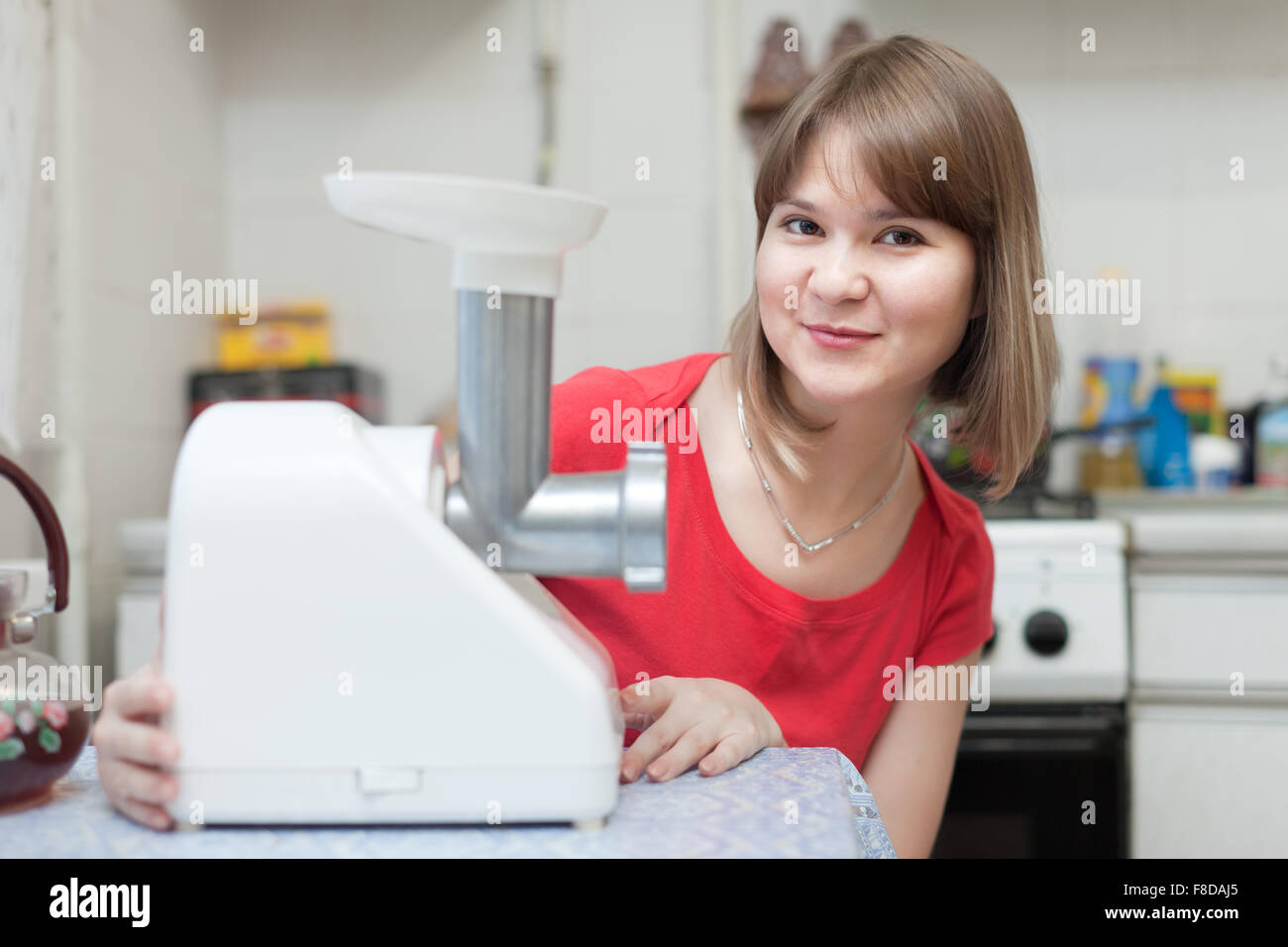 Young woman with electric meat comminutor at home Stock Photo