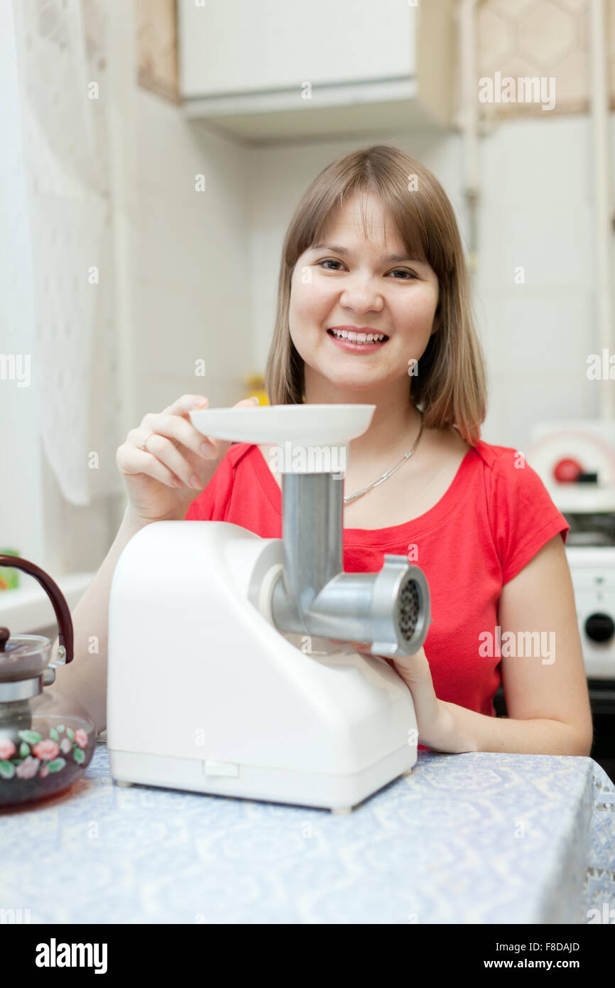 Young woman with electric meat grinder at home Stock Photo