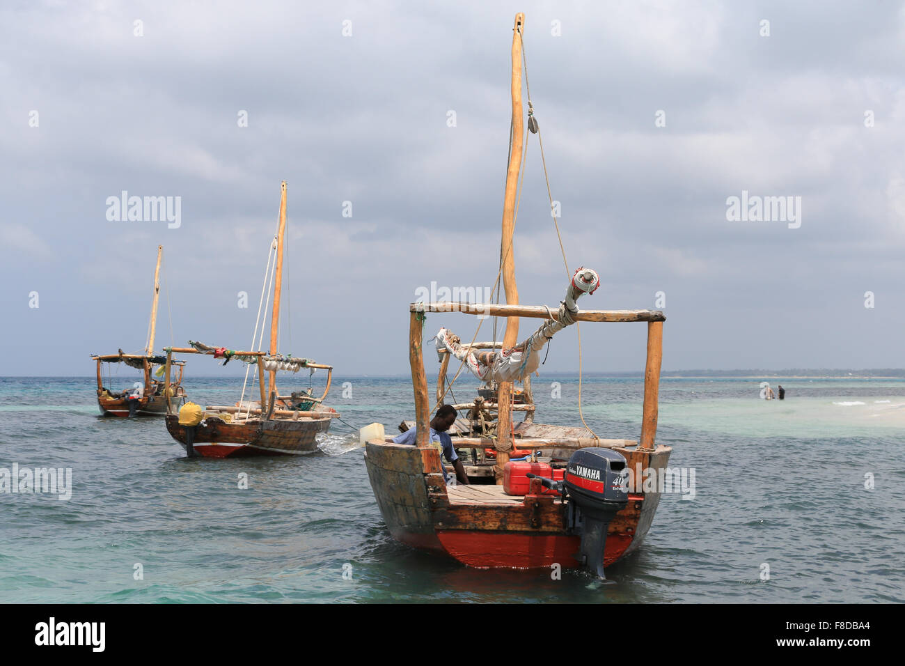 Man bailing water from a dhow anchored near tiny islet north of Kwale Island and south of Zanzibar, Tanzania, East Africa. Stock Photo