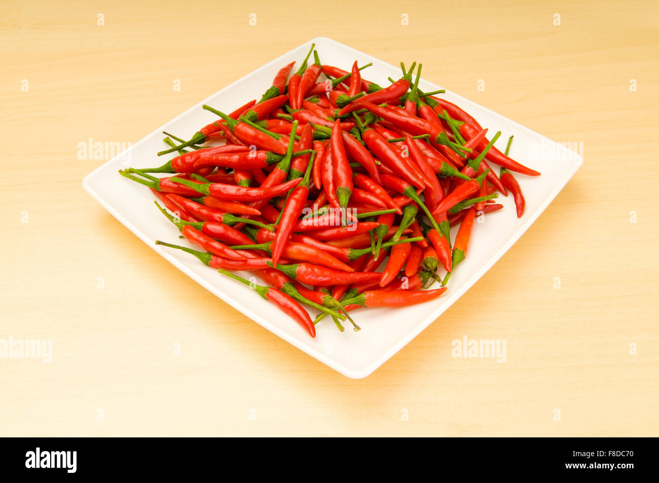 Table Peper Hot peppers in the plate on wooden table Stock Photo - Alamy