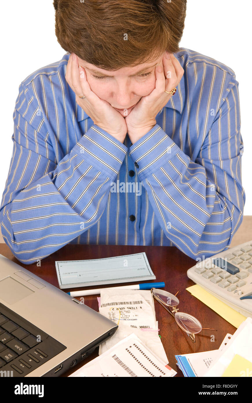 A middle aged woman holding her head in her hands having financial worries. Stock Photo