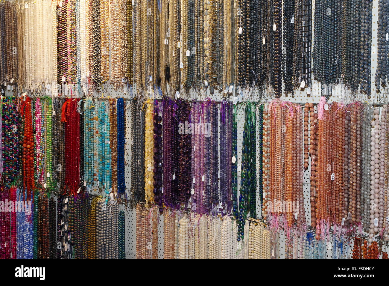 Beads made of semiprecious stones hanging on display at a market stall. Stock Photo