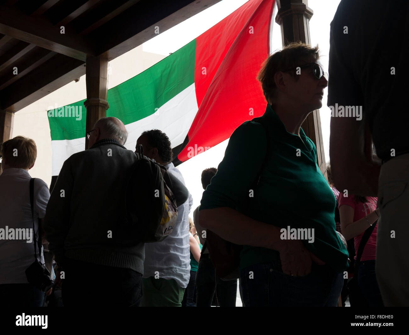 Tourists waiting for tour bus pickup under United Arab Emirates flag in Dubai, UAE. Stock Photo