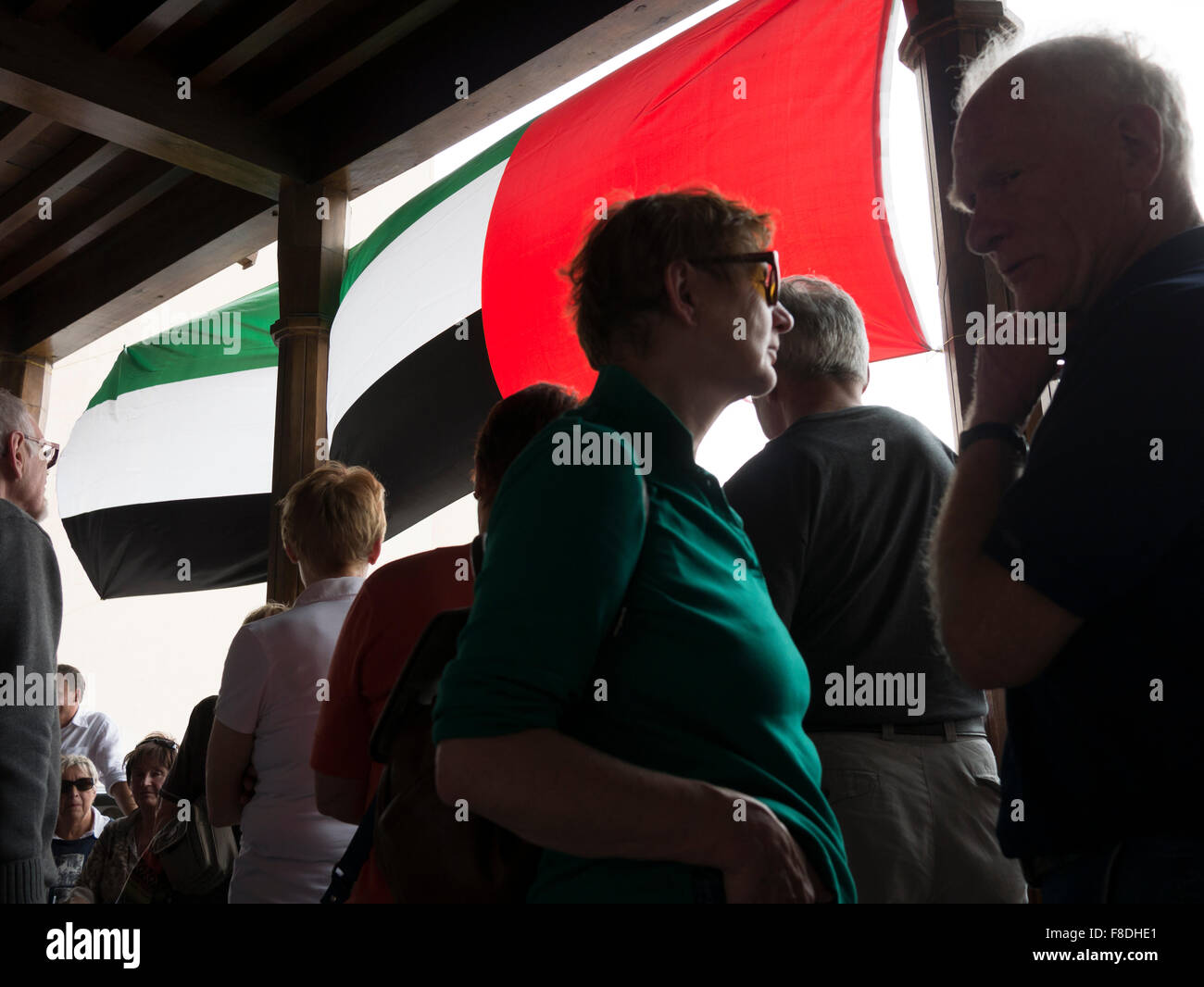Tourists waiting for tour bus pickup under United Arab Emirates flag in Dubai, UAE. Stock Photo
