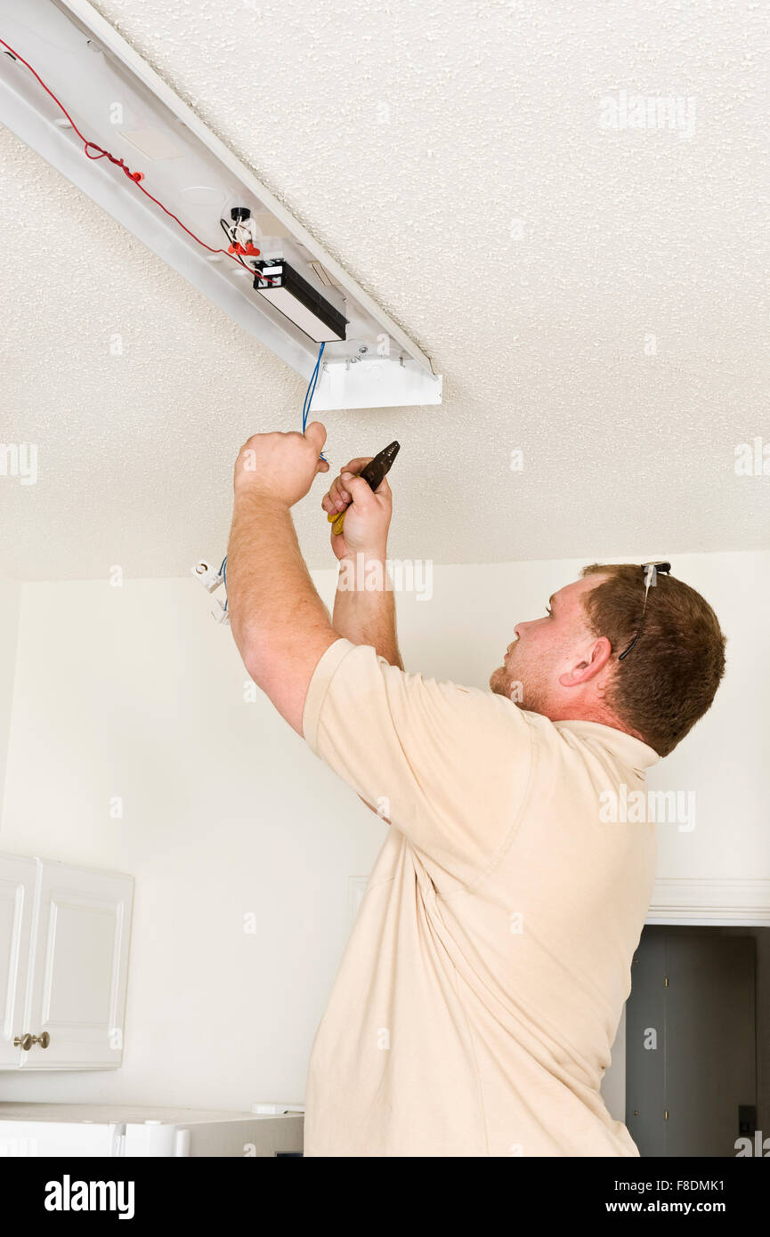 A Male Electrician Installing Fluorescent Lighting Fixture Stock A Male Electrician Installing Fluorescent Lighting Fixture