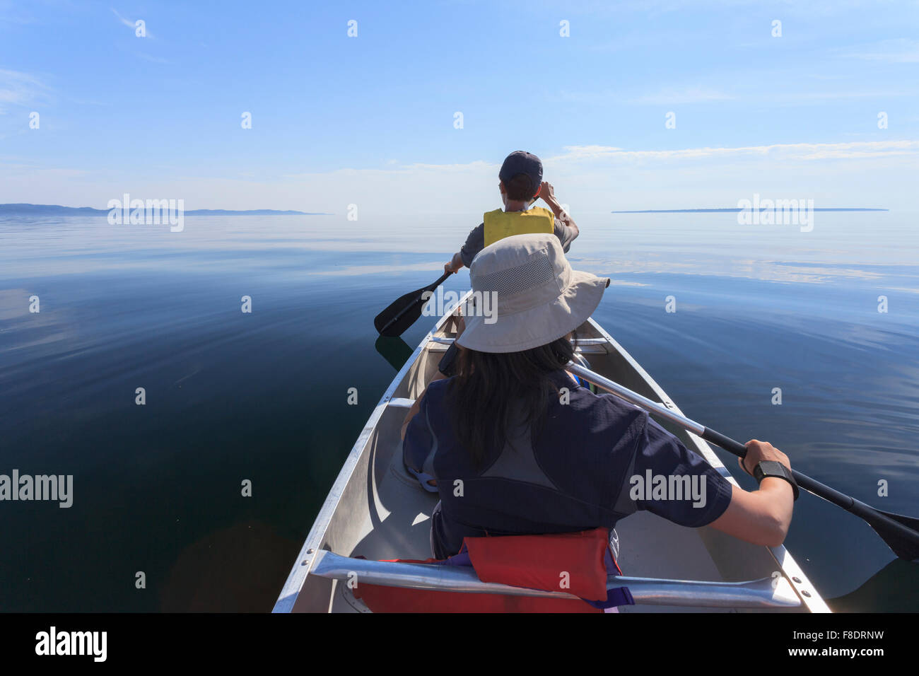 Asian family paddles in the Lake Superior Provincial Park in a calm summer afternoon Stock Photo