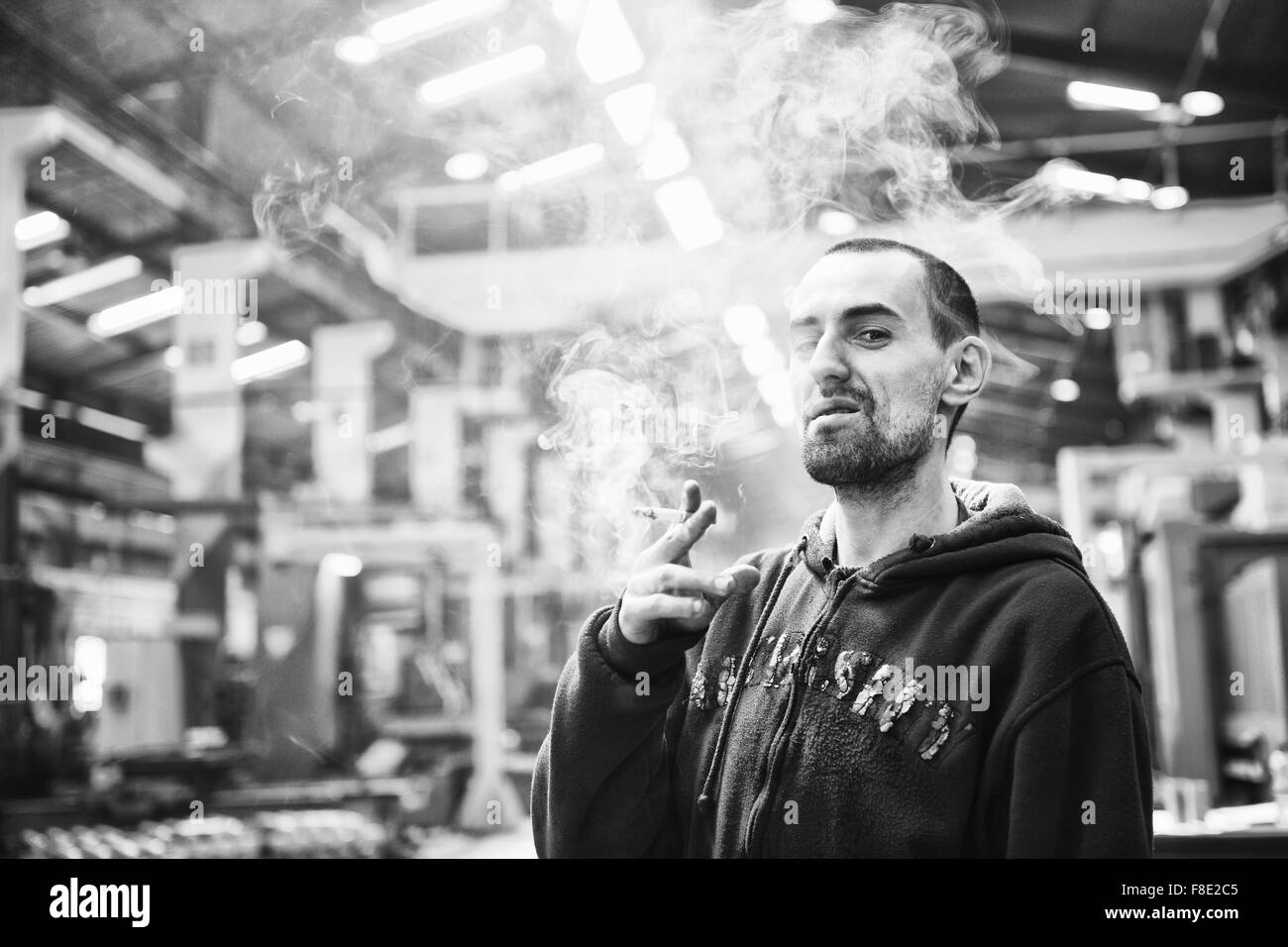 industry worker smoke cigarette at job in company at big bright hall Stock Photo