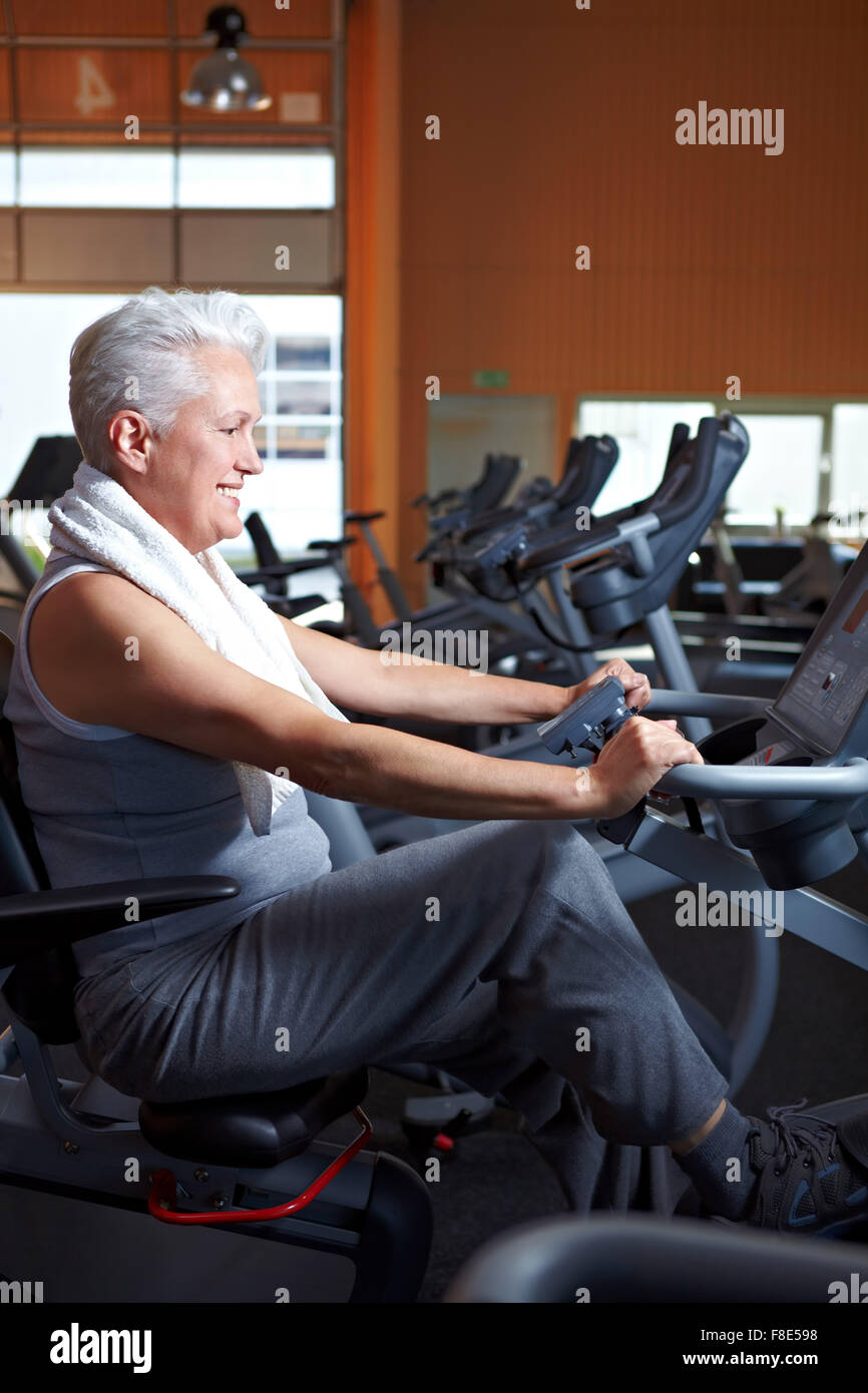 Elderly woman exercising on bicycle in a gym Stock Photo - Alamy
