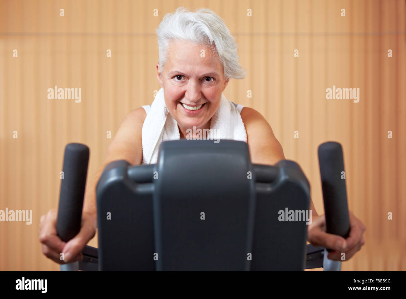 Elderly woman exercising on bicycle in a gym Stock Photo - Alamy