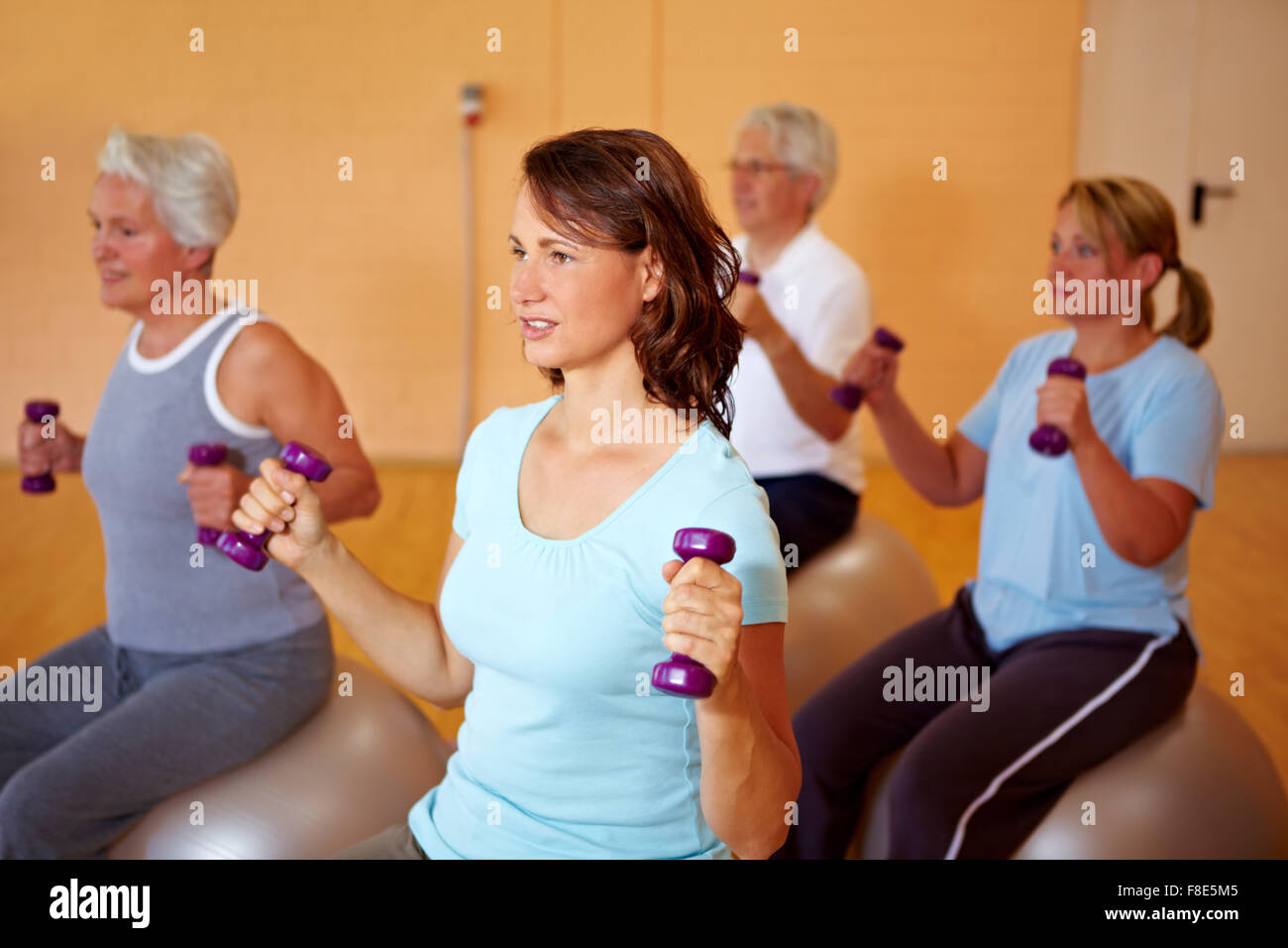 Group in gym doing dumbbell training on Swiss balls Stock Photo - Alamy