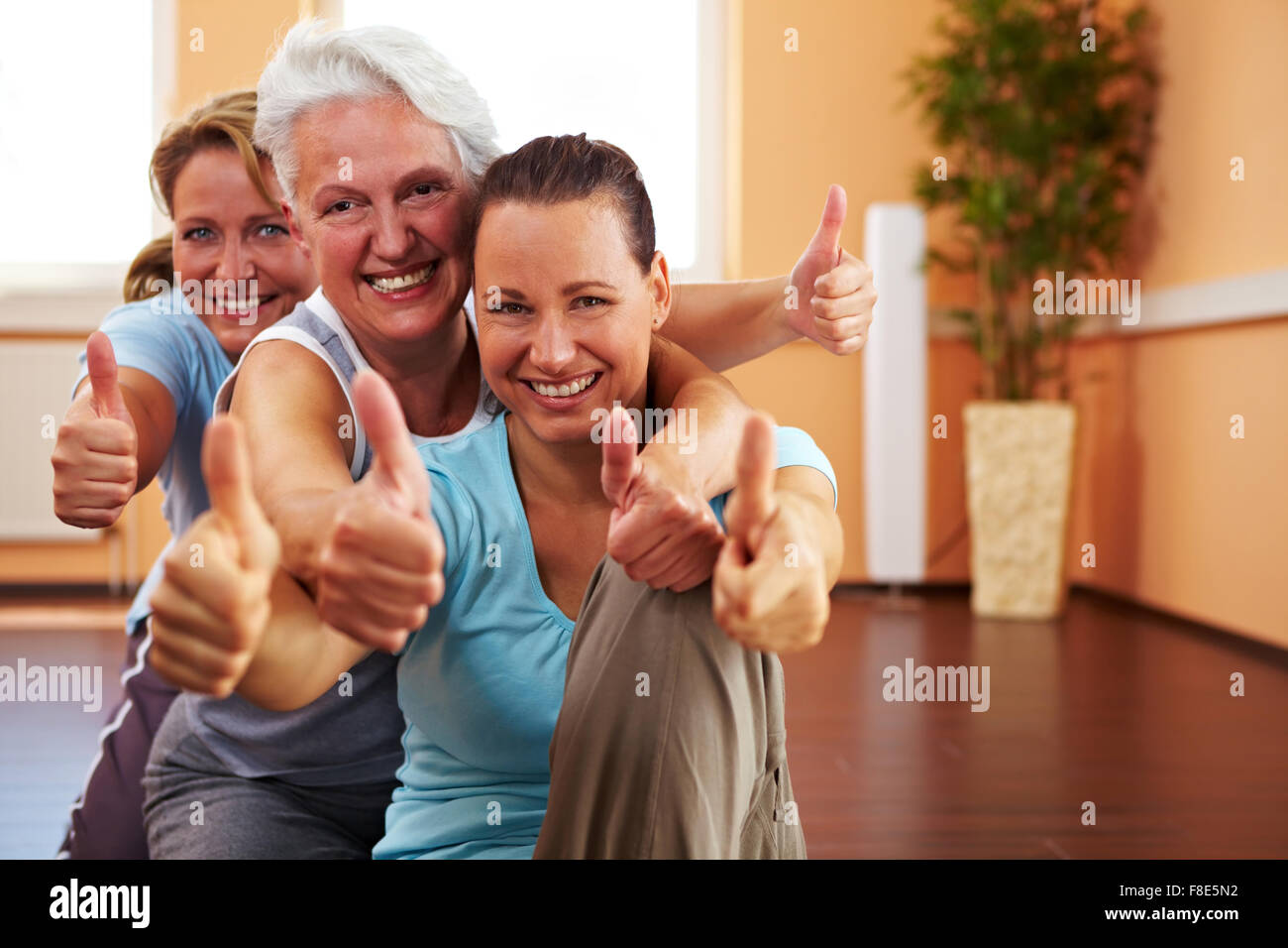 Three happy women in a gym holding their thumbs up Stock Photo