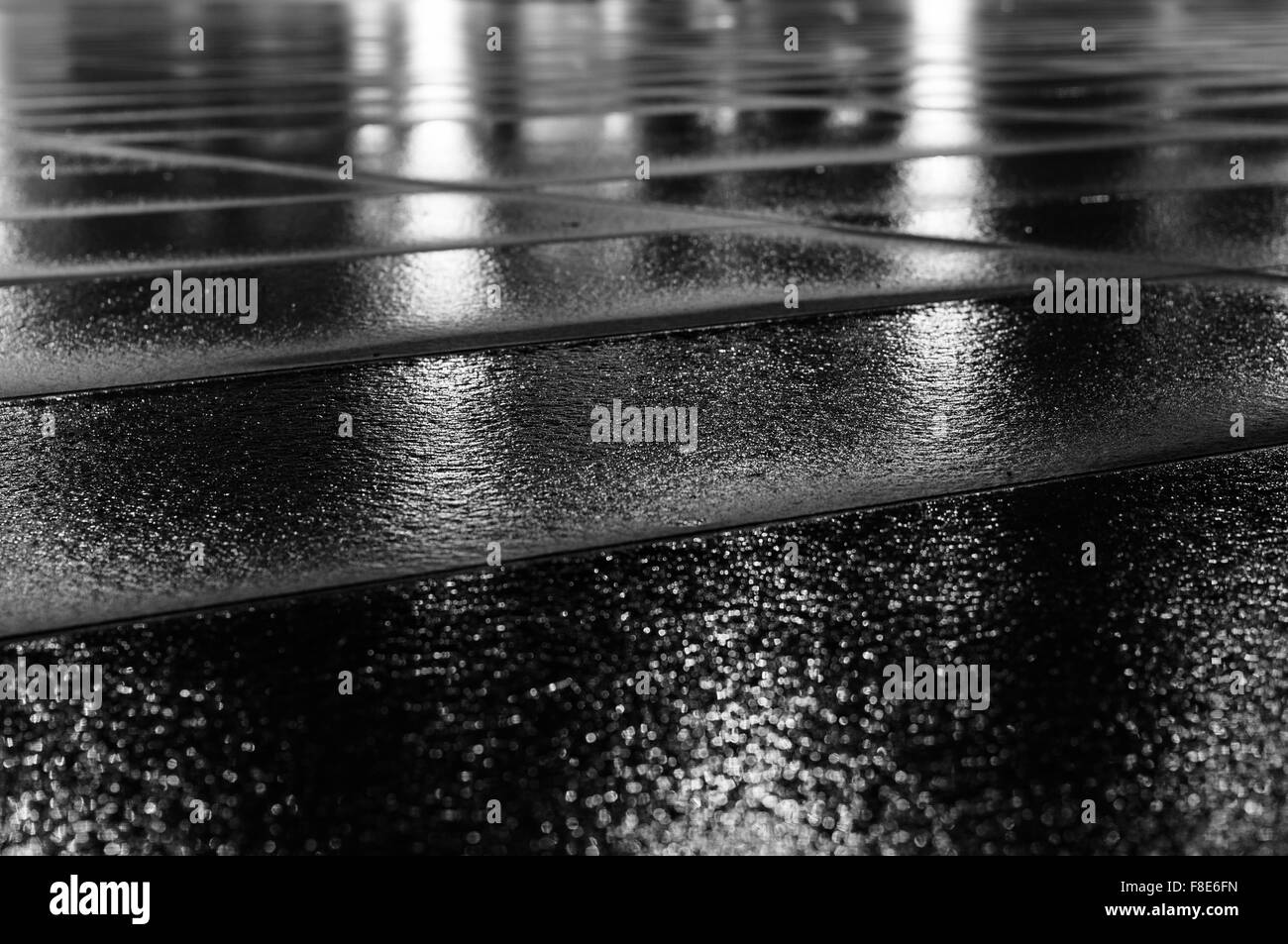Night light reflection on wet paving slab after rain. Black and white image with selective focus Stock Photo