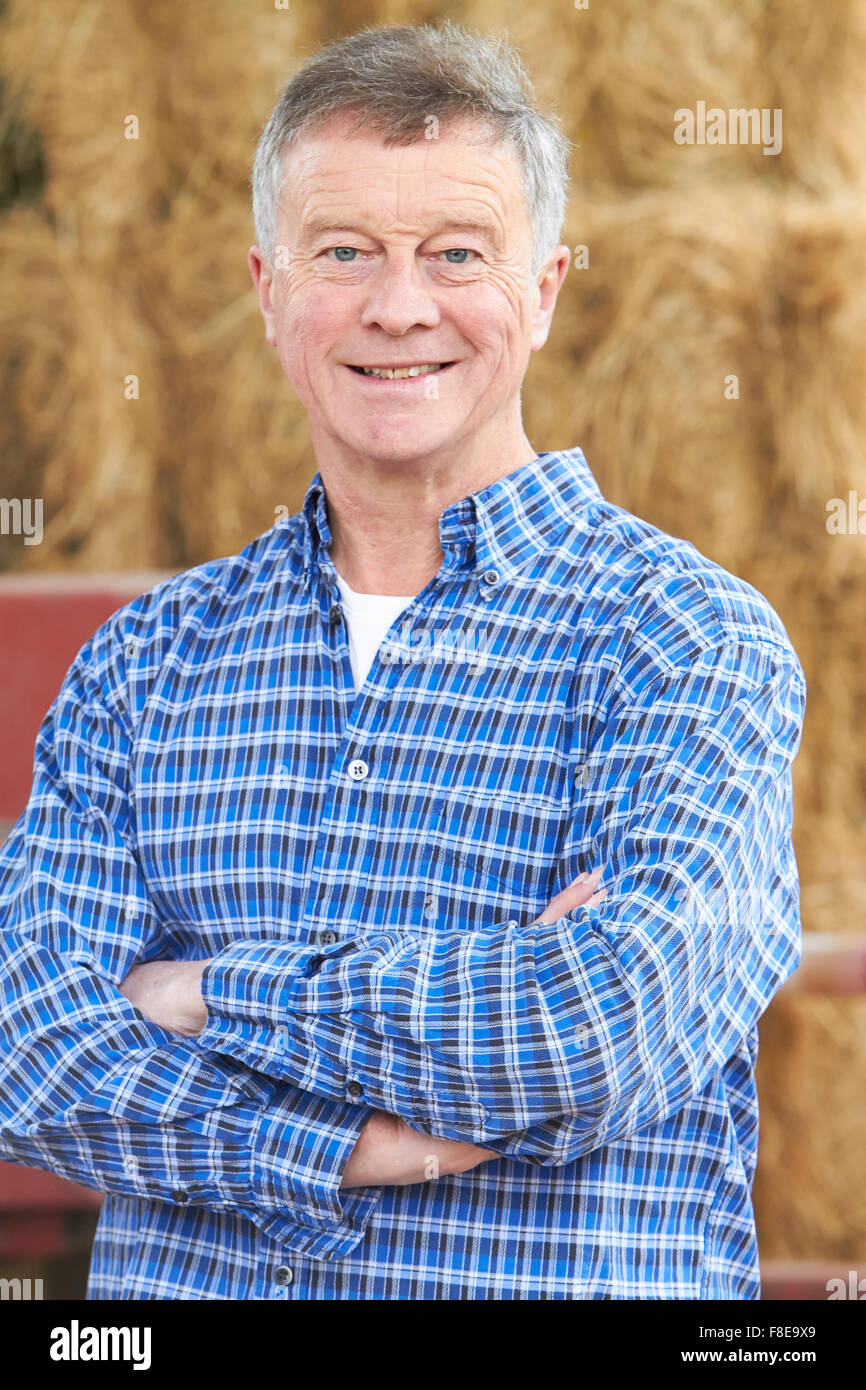 Farmer Standing In Front Of Bales And Old Farm Equipment Stock Photo ...
