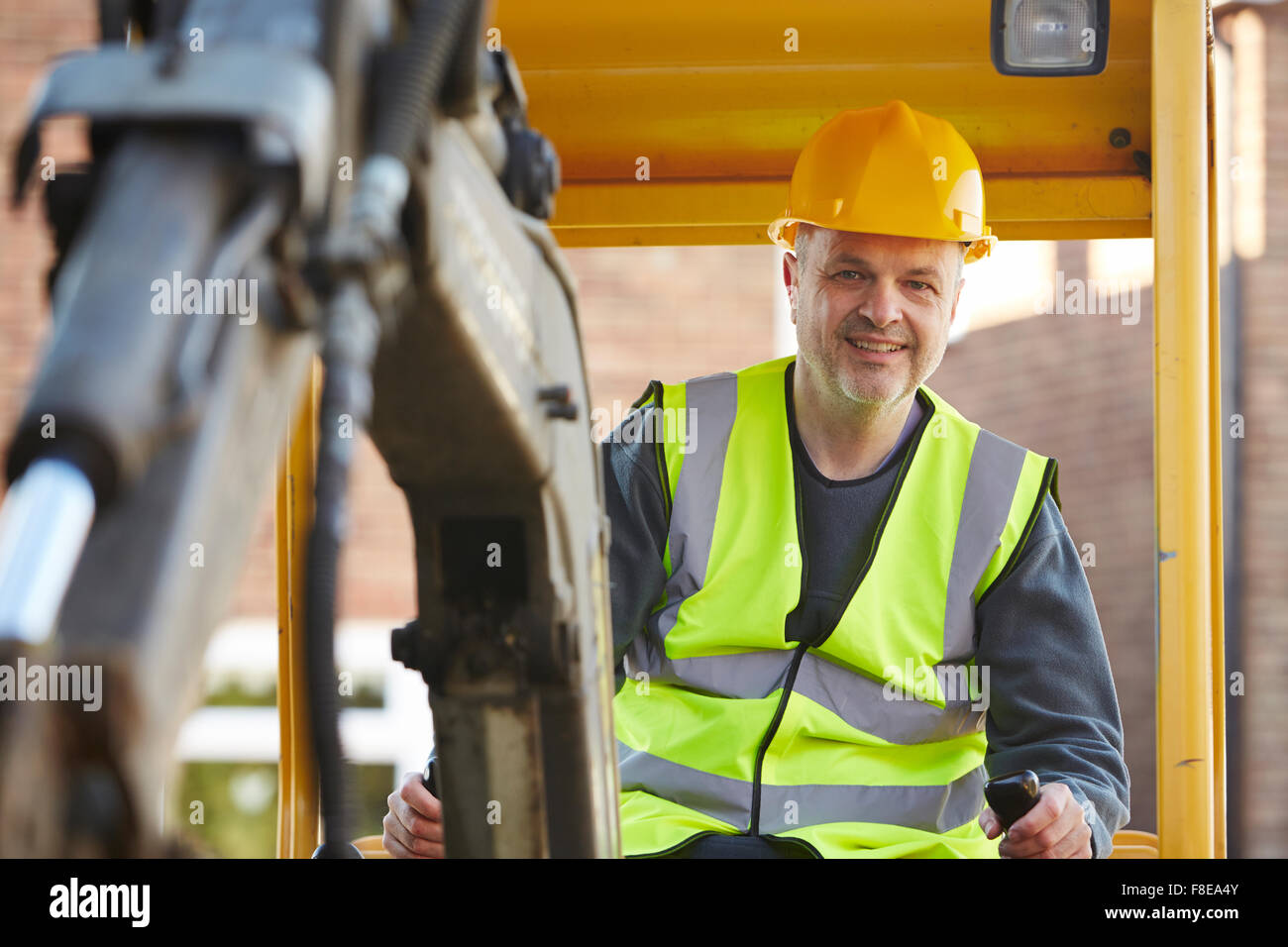 Construction Worker Operating Digger On Site Stock Photo
