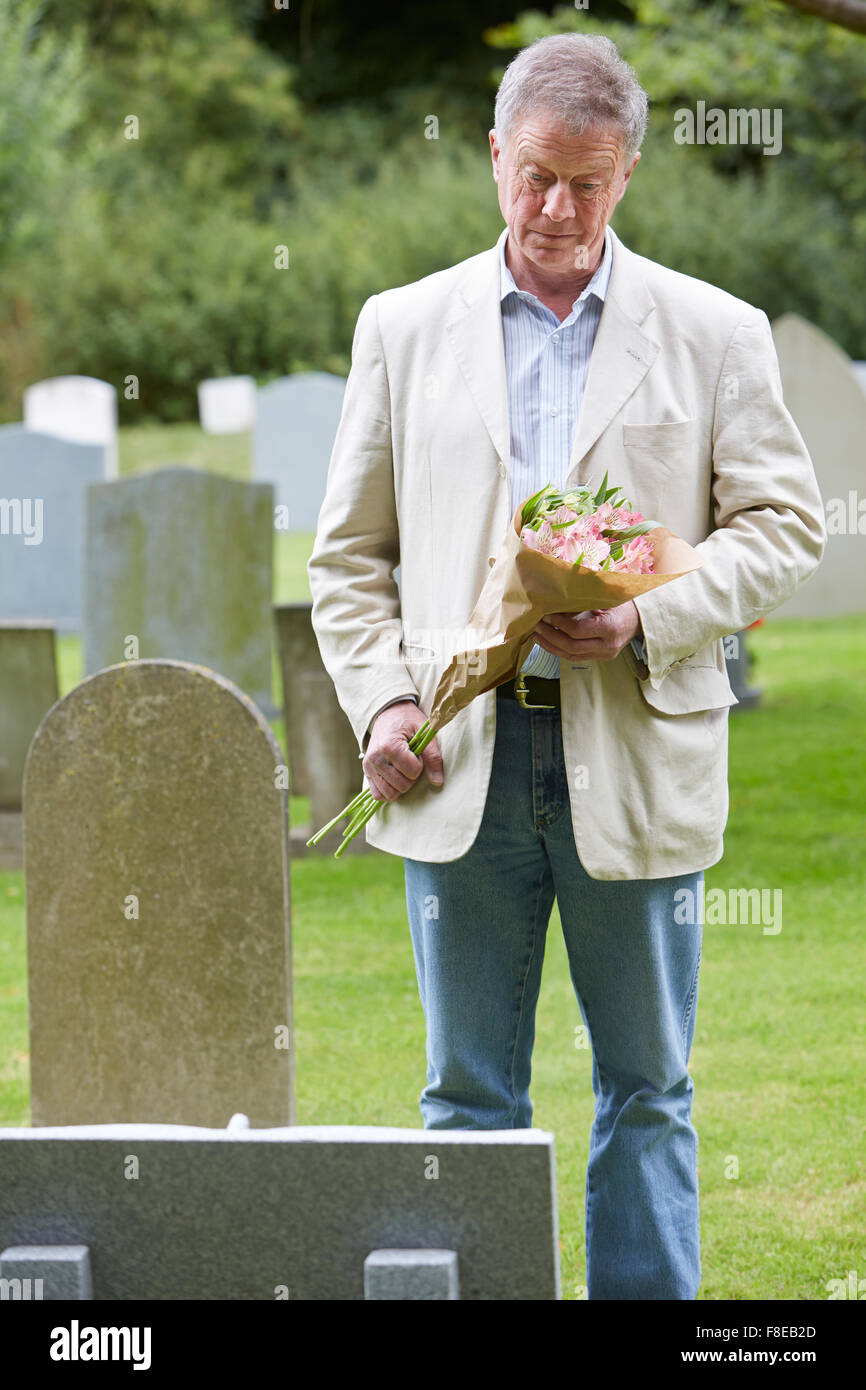 Senior Man Laying Flowers on Grave Stock Photo