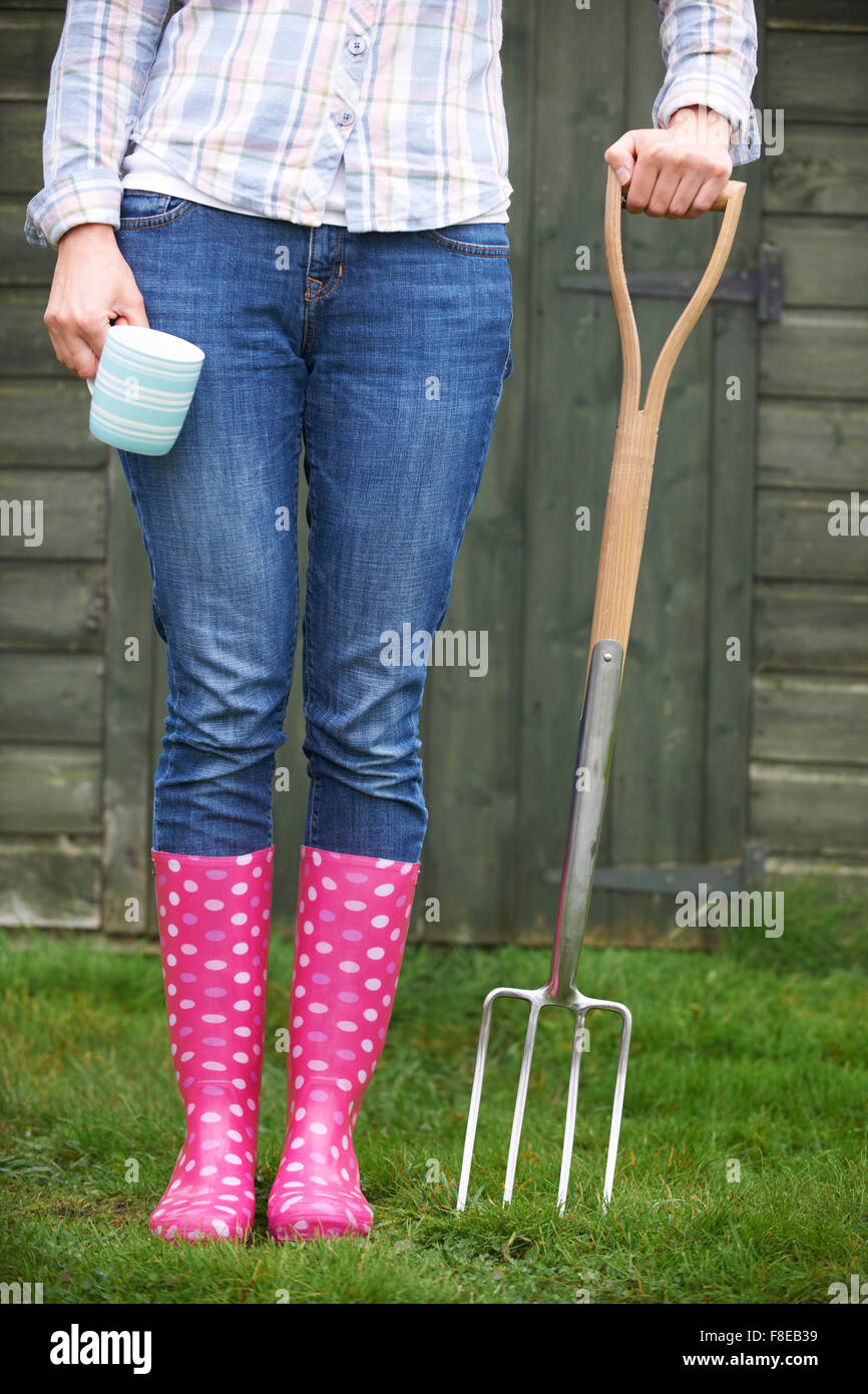 Woman In Pink Wellingtons Holding Garden Fork And Cup Stock Photo