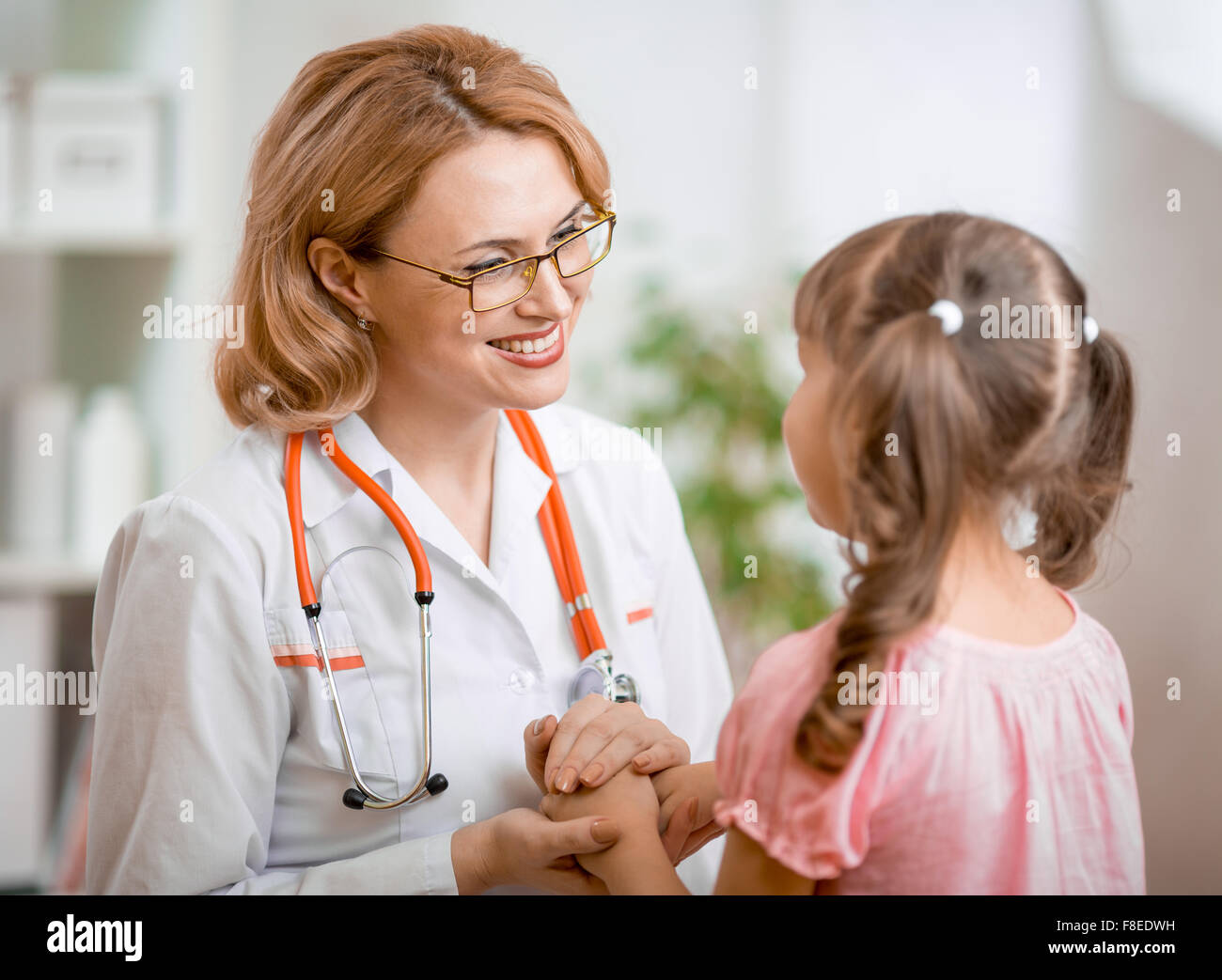 Positive pediatrician doctor examining kid Stock Photo