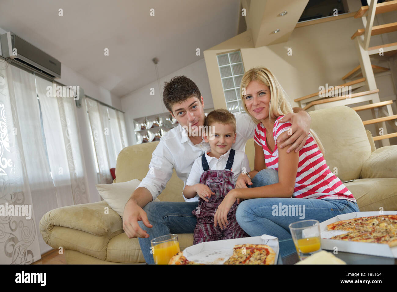 happy young family eating tasty pizza with cheesa and dring healthy and fresh orange juice Stock Photo
