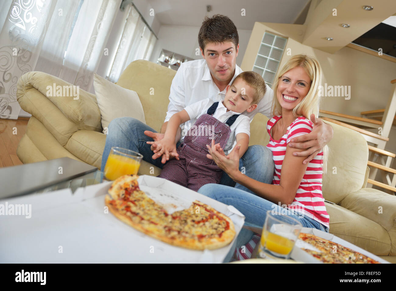 happy young family eating tasty pizza with cheesa and dring healthy and  fresh orange juice Stock Photo - Alamy