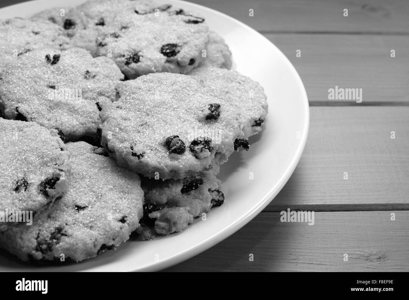 Close up of delicious traditional Easter currant biscuits on a plate, on a wooden kitchen table - monochrome processing Stock Photo