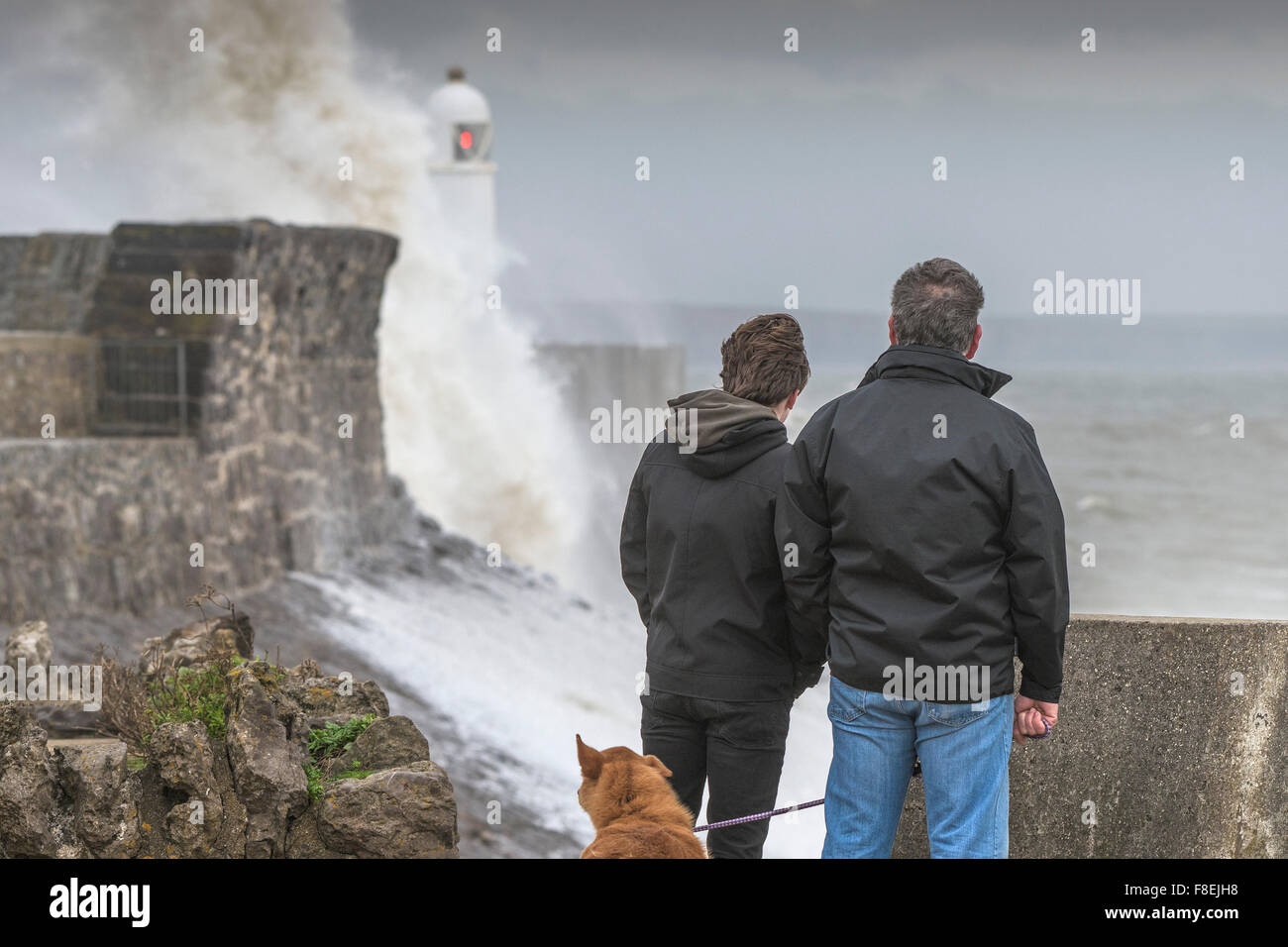 People watching huge waves crash over the quay and lighthouse on the seafront in Porthcawl, South Wales. Stock Photo