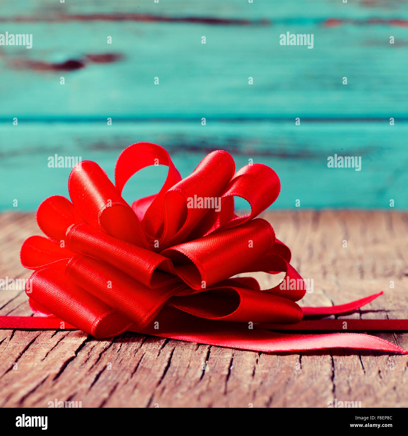 a red satin ribbon bow on an old rustic wooden surface Stock Photo - Alamy