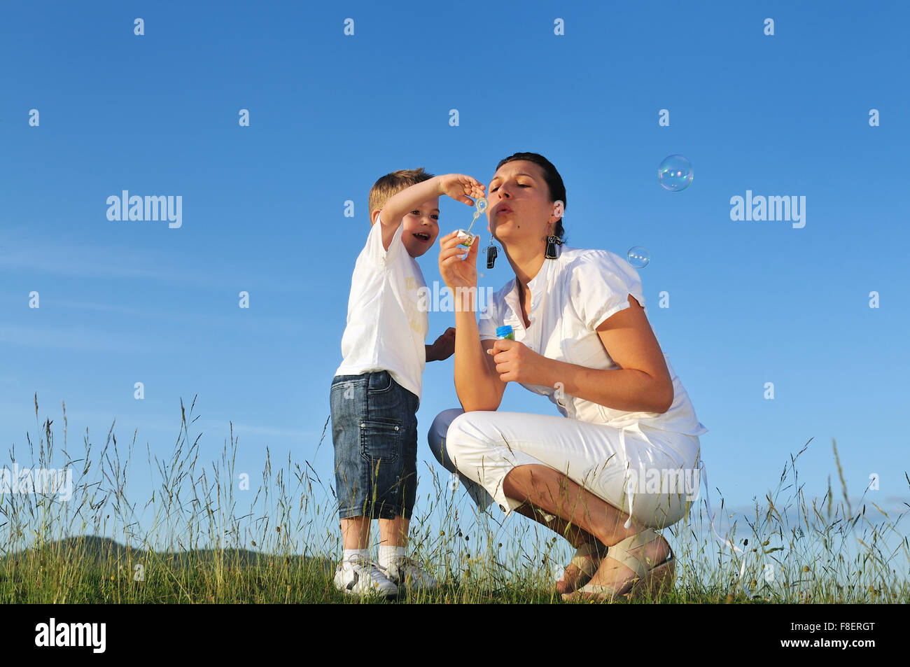 happy child and woman outdoor playing with soap bubble on meadow Stock ...