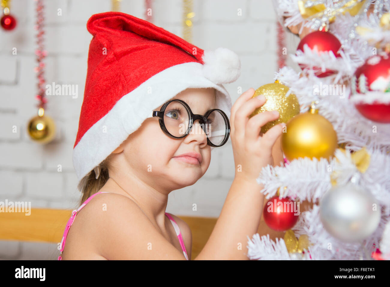 Four-year girl hangs balls on the Christmas tree Christmas snow Stock Photo