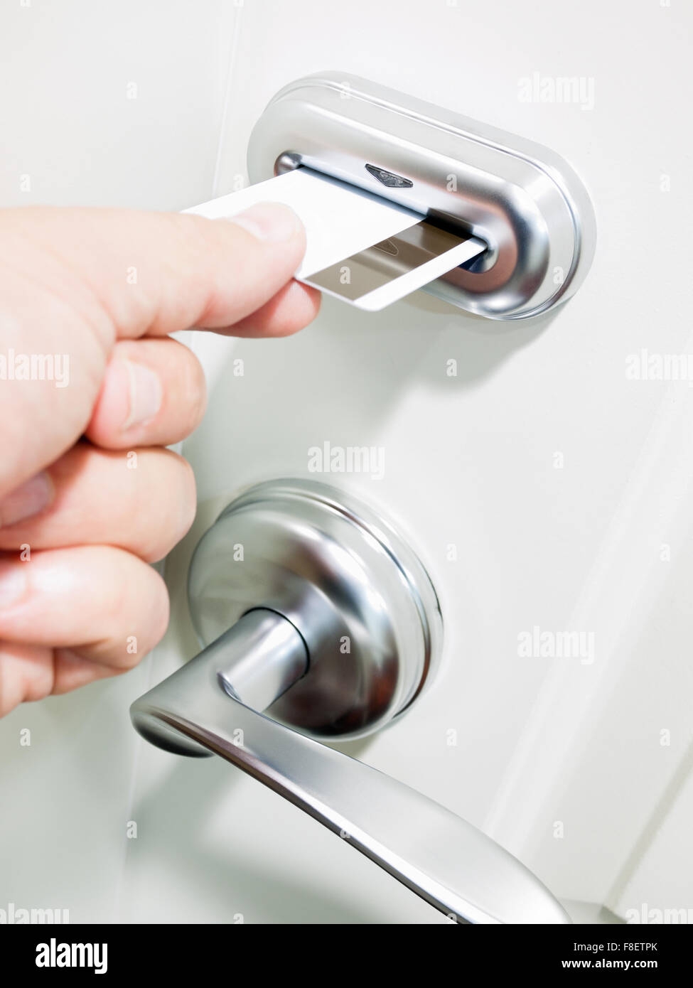 Person's hard unlocking a hotel room electronic door lock by inserting a keycard Stock Photo