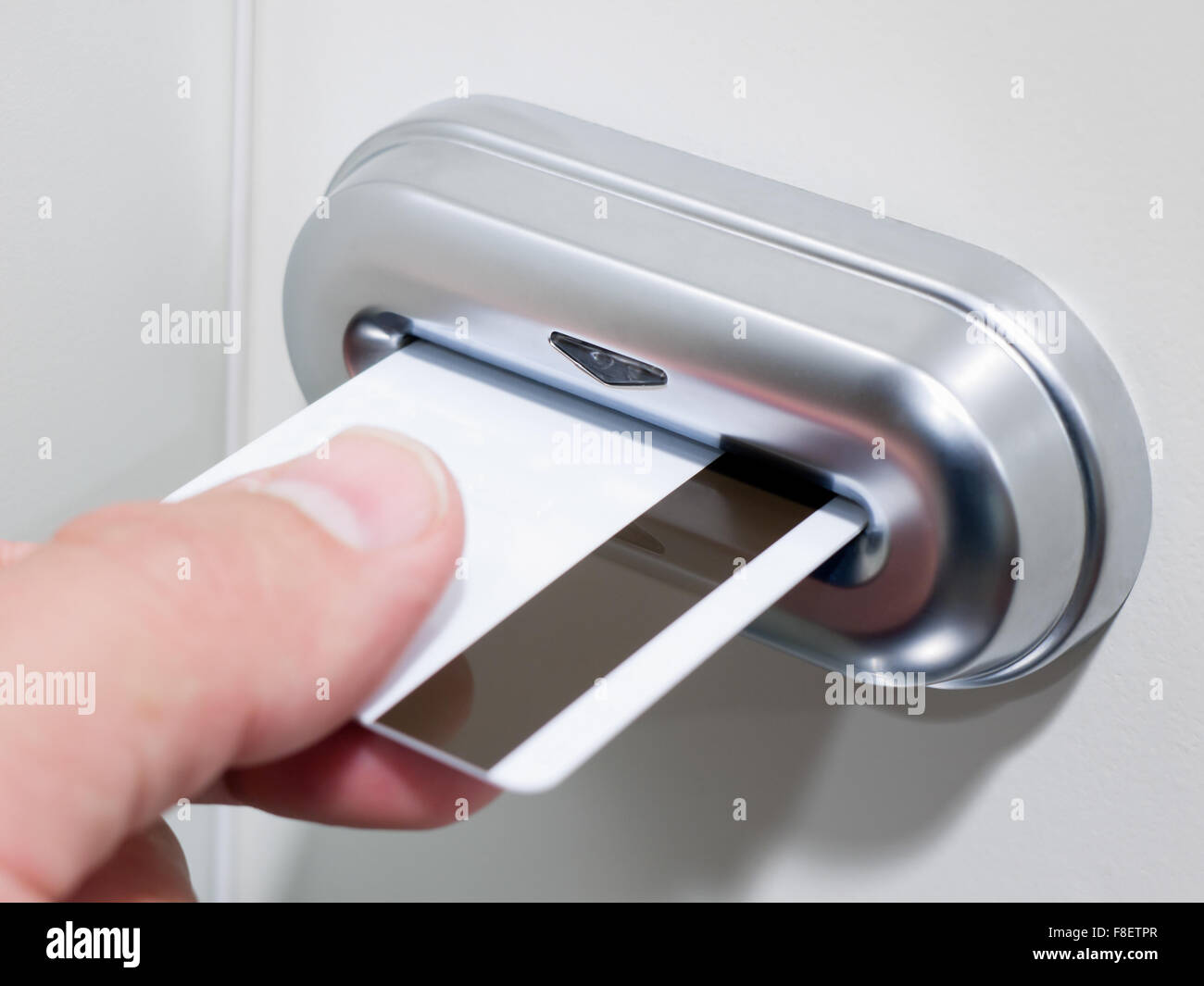Person's hand inserting a magnetic stripe keycard into an electronic card key door lock Stock Photo