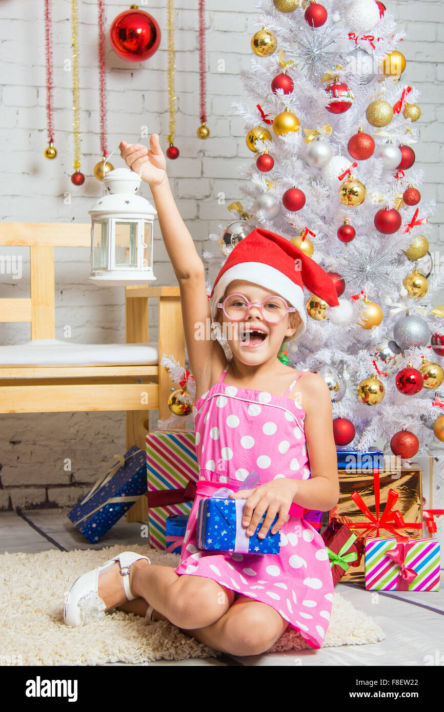 Six year old girl sitting on a mat at a snowy Christmas trees Stock Photo