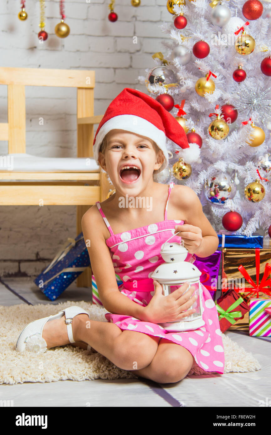 Six year old girl sitting on a mat at a snowy Christmas trees Stock Photo