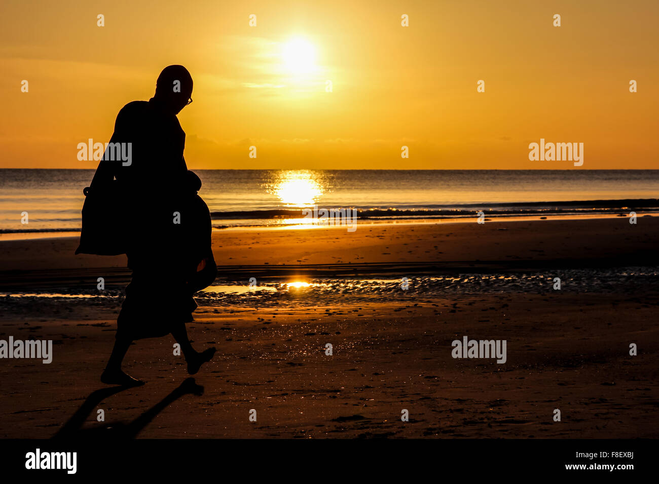 Silhouette of monk walk on the beach , Huahin , Thailand Stock Photo