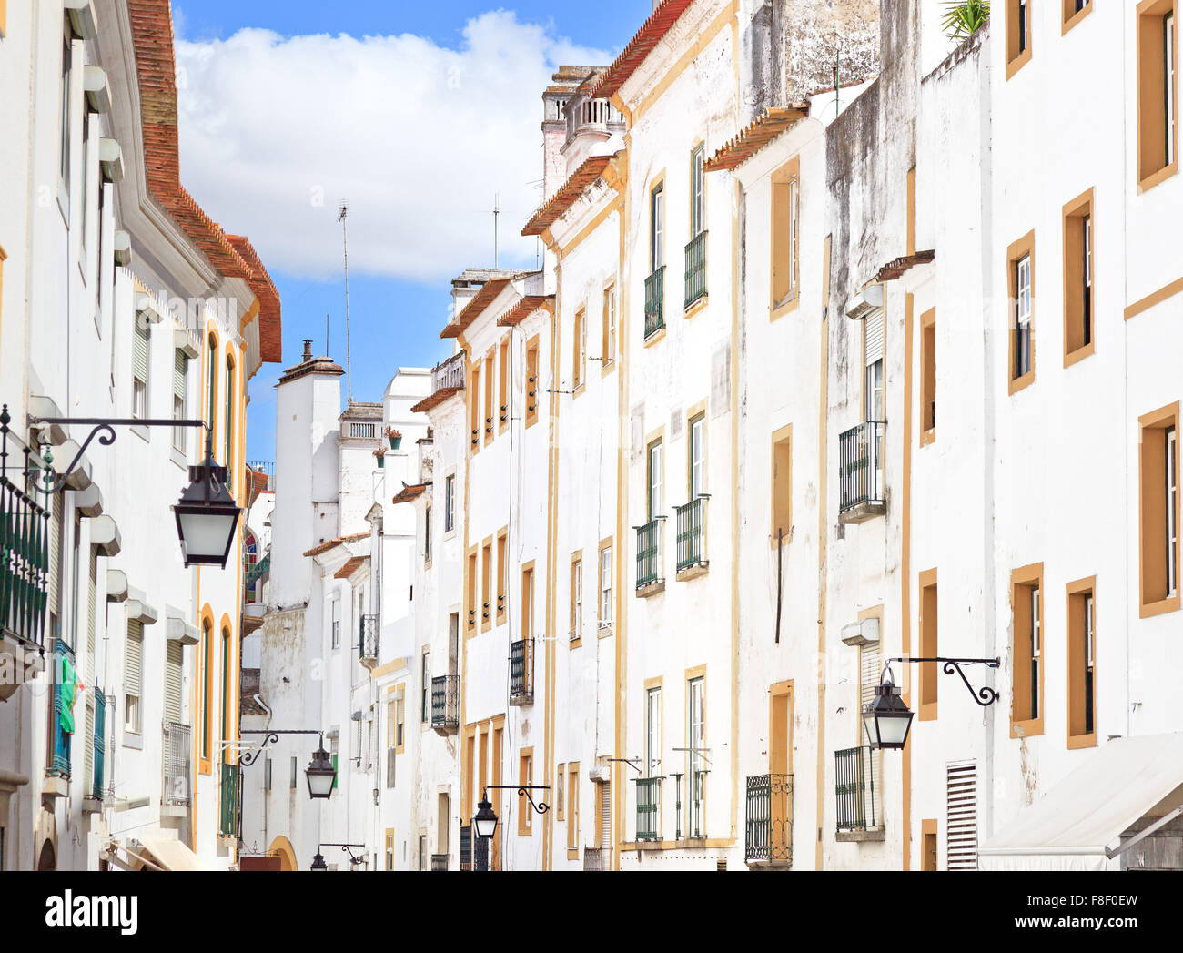 White facades and colorful windows. Old urban street in Evora town. Alentejo, Portugal, Europe. Stock Photo