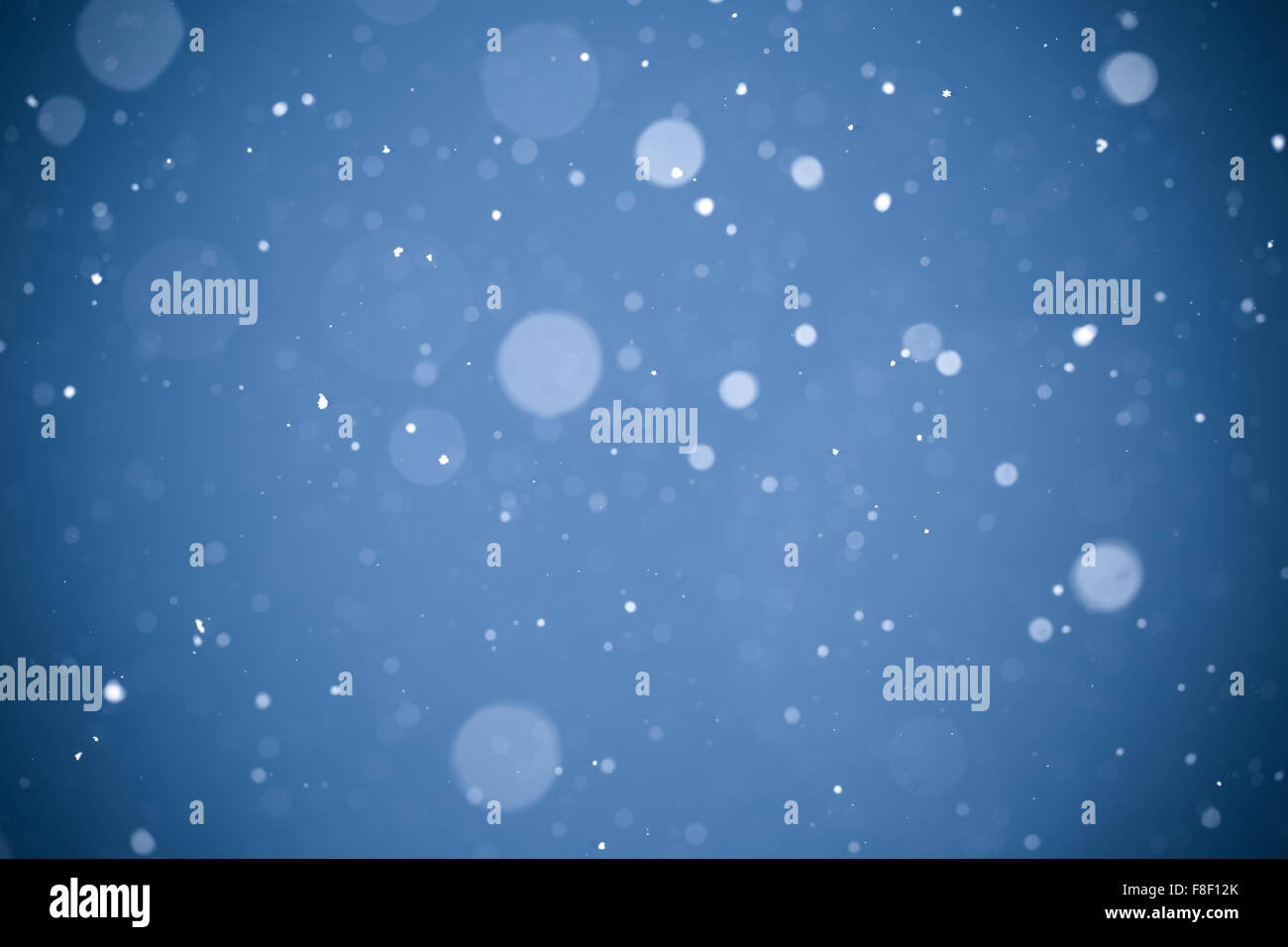 Falling snow on blue background Stock Photo - Alamy