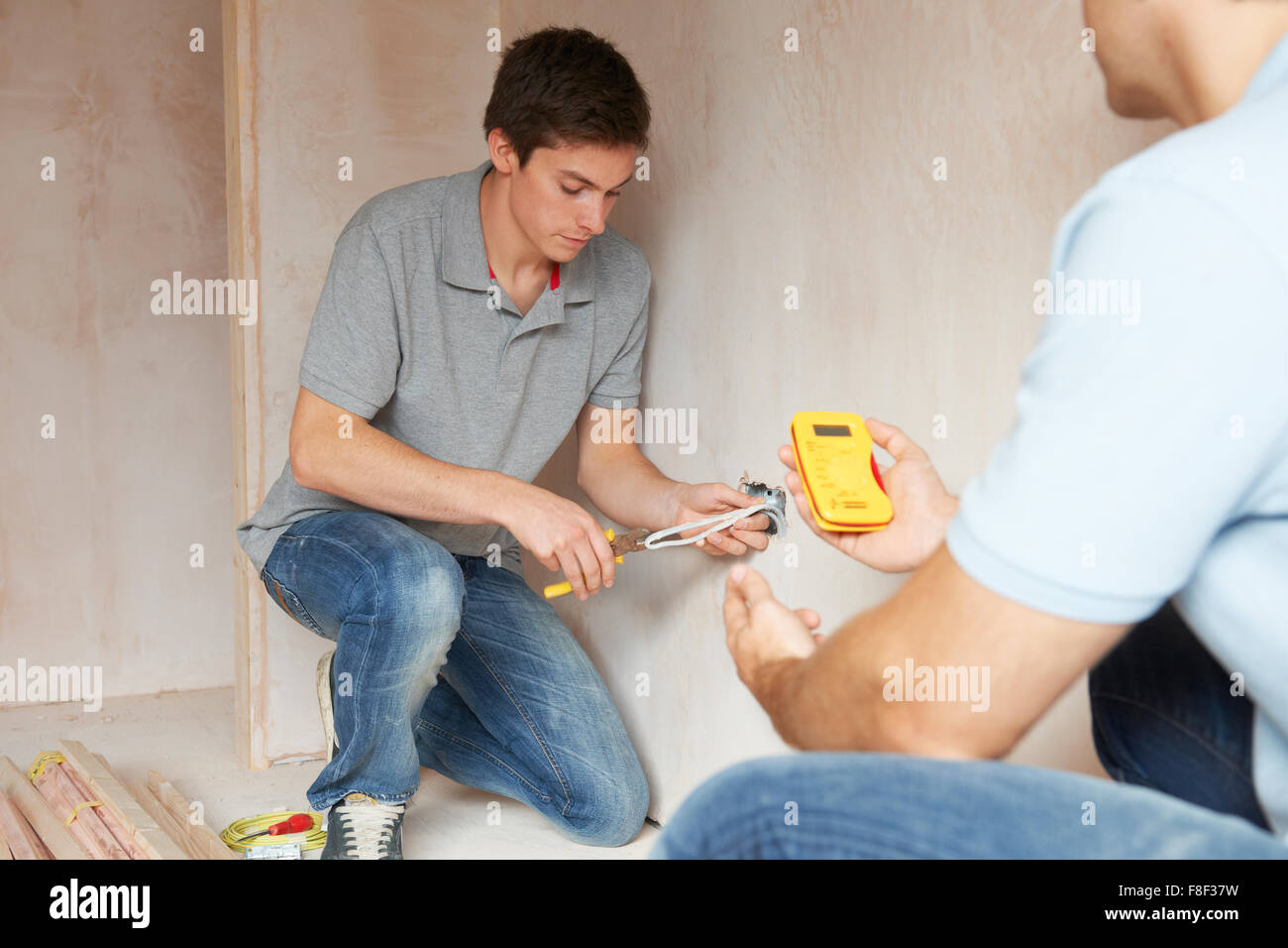 Electrician With Apprentice Working In New Home Stock Photo