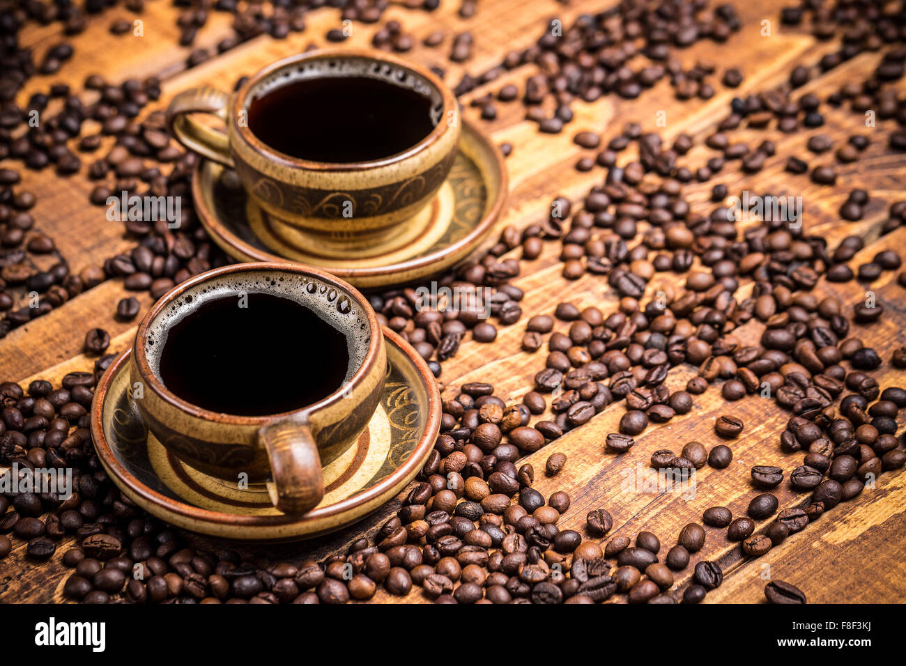 Cups of coffee on wooden table with scattered beans Stock Photo