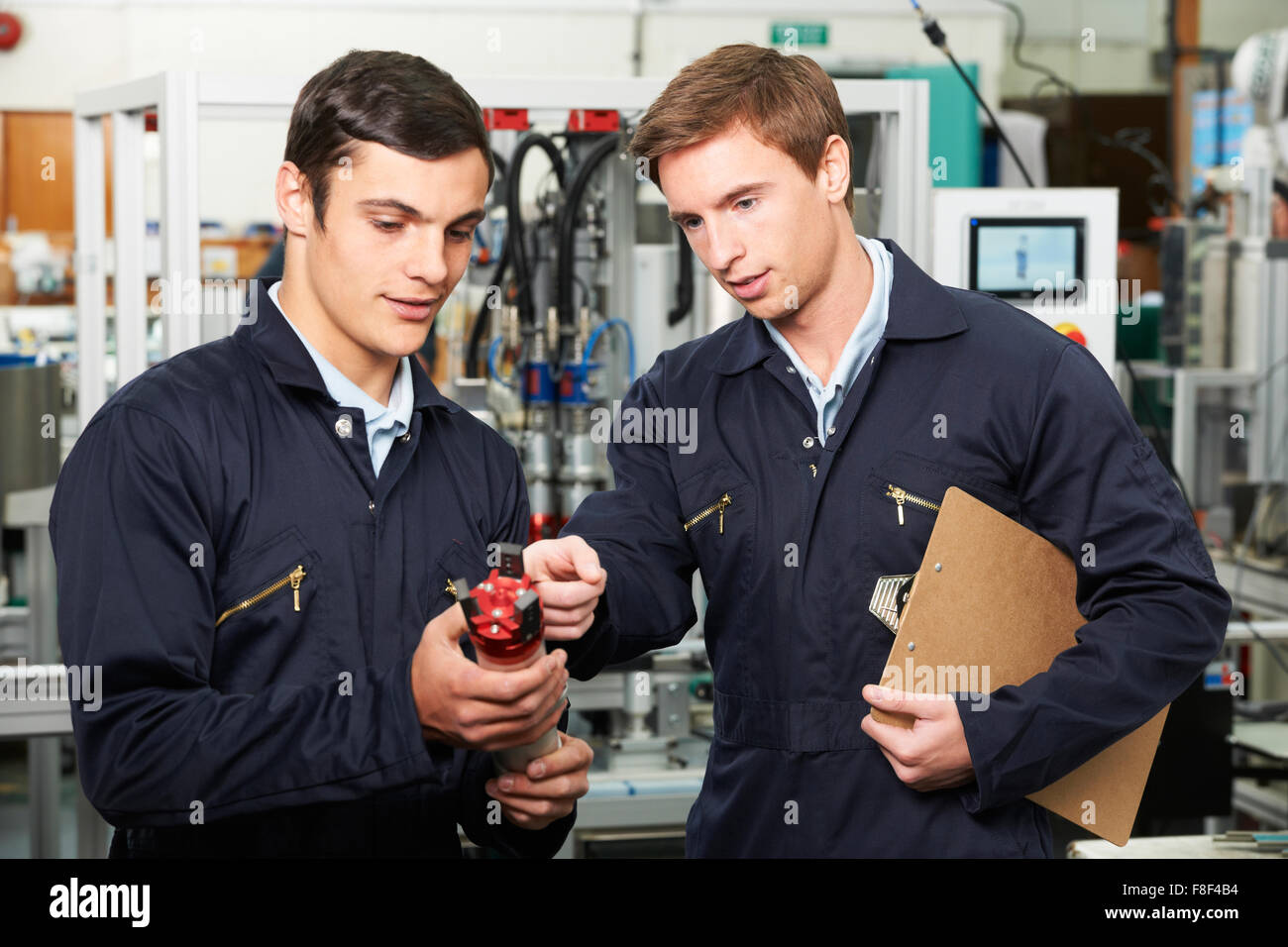 Engineer And Trainee Discussing Component In Factory Stock Photo