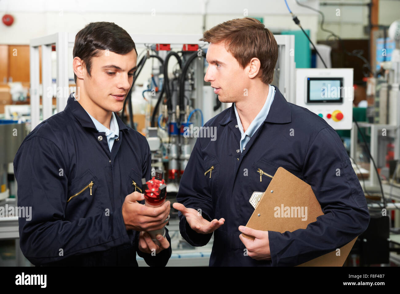 Engineer And Trainee Discussing Component In Factory Stock Photo
