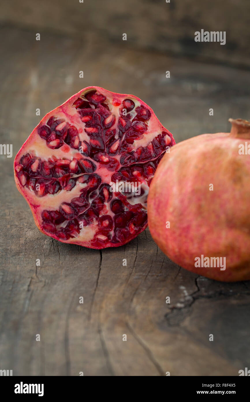 Whole and a half pomegranate on a rustic wooden table Stock Photo