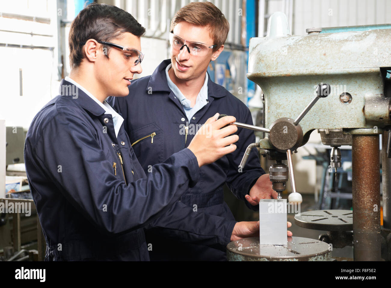 Engineer And Apprentice Using Machinery In Factory Stock Photo