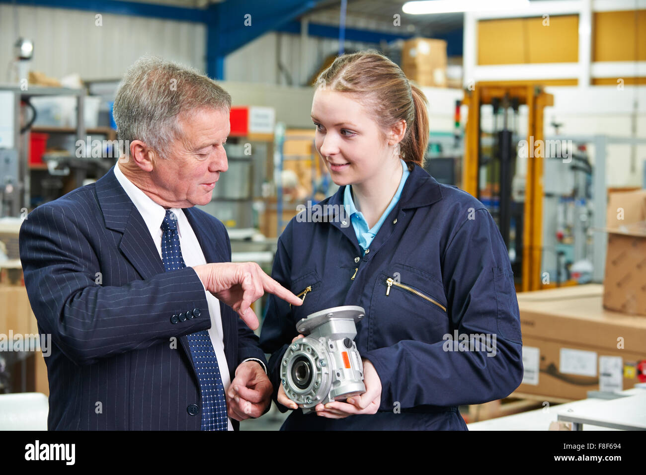 Factory Manager And Engineering Apprentice Discussing Component Stock Photo