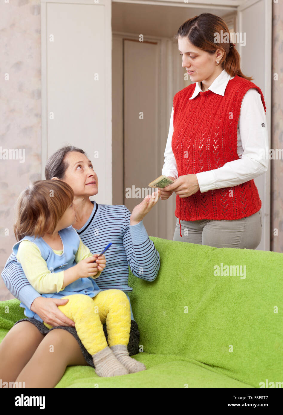 mother leaving baby with nanny at home. Focus on adults Stock Photo
