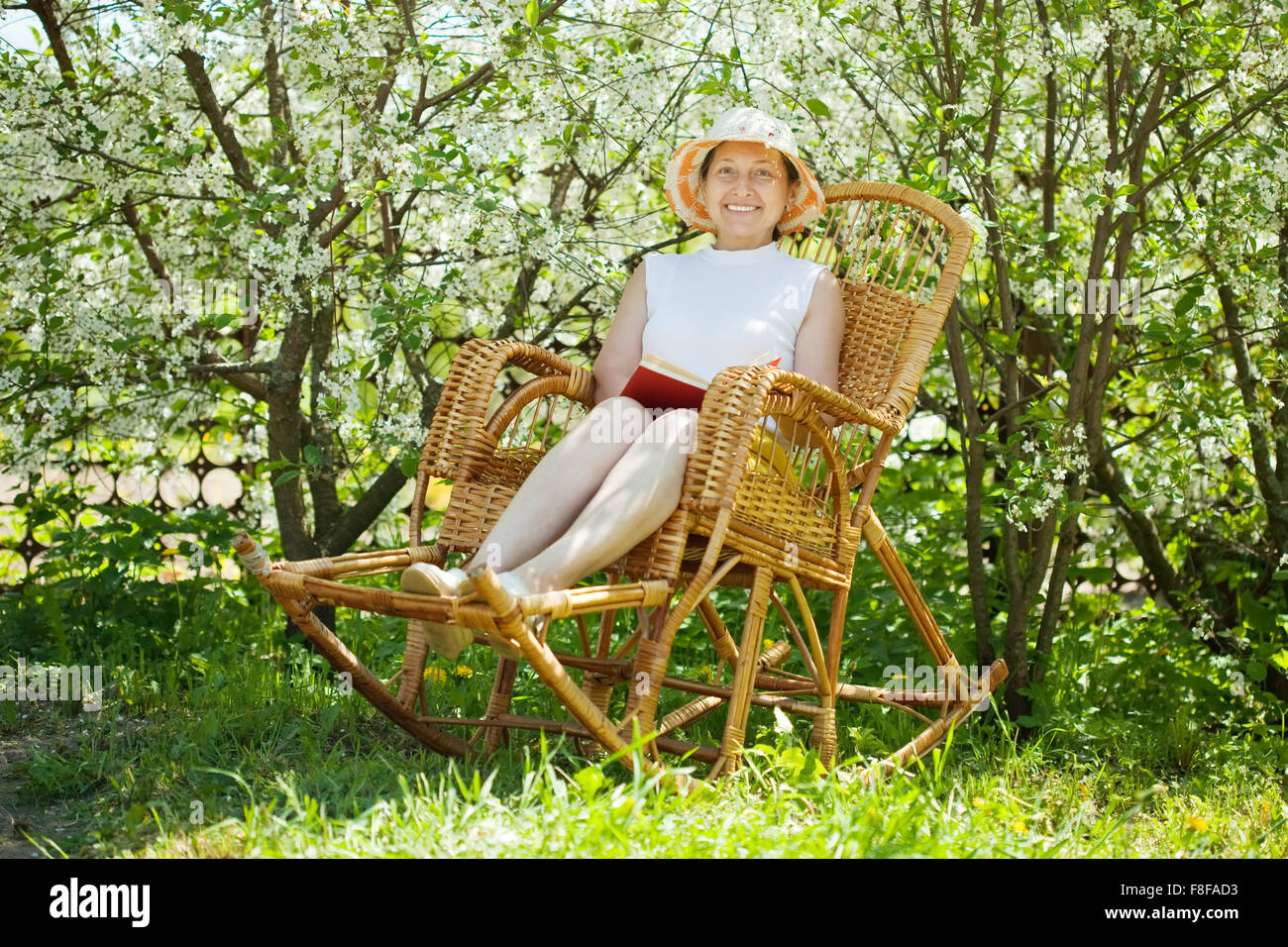 Mature woman reading book in blossoming garden Stock Photo - Alamy