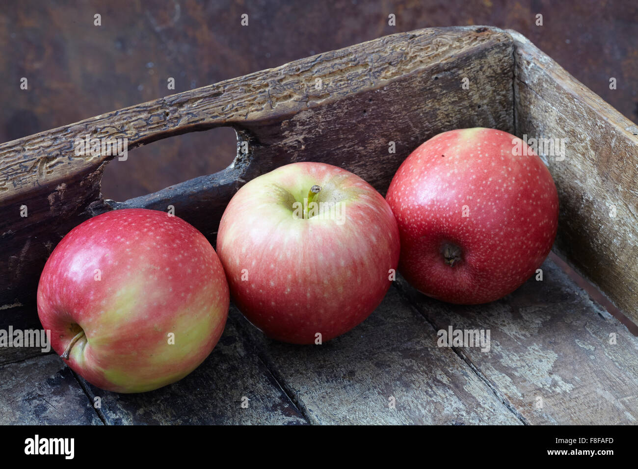 Three apples in weathered wooden box Stock Photo Alamy