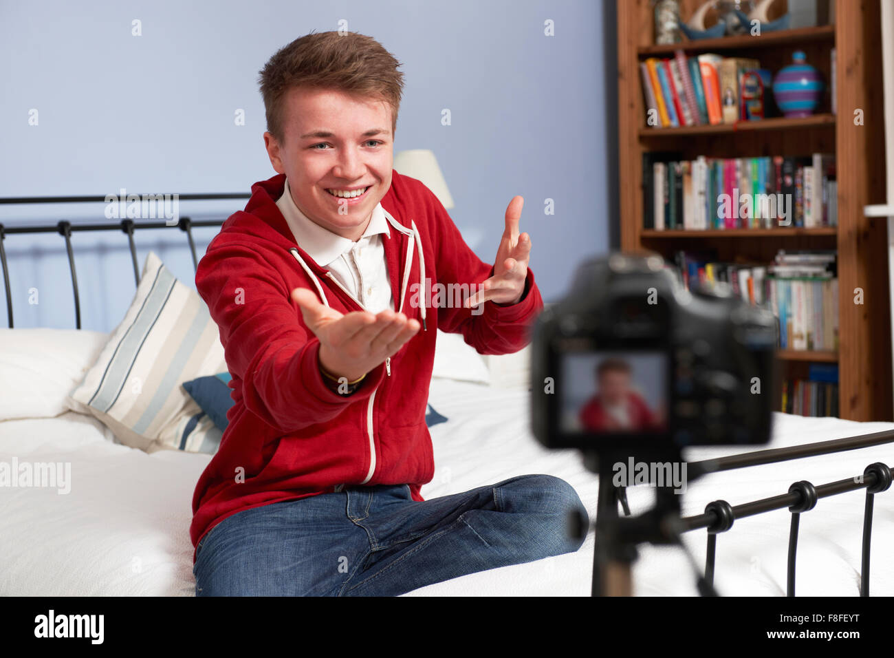 Teenage Boy Recording Video Of Himself In Bedroom Stock Photo