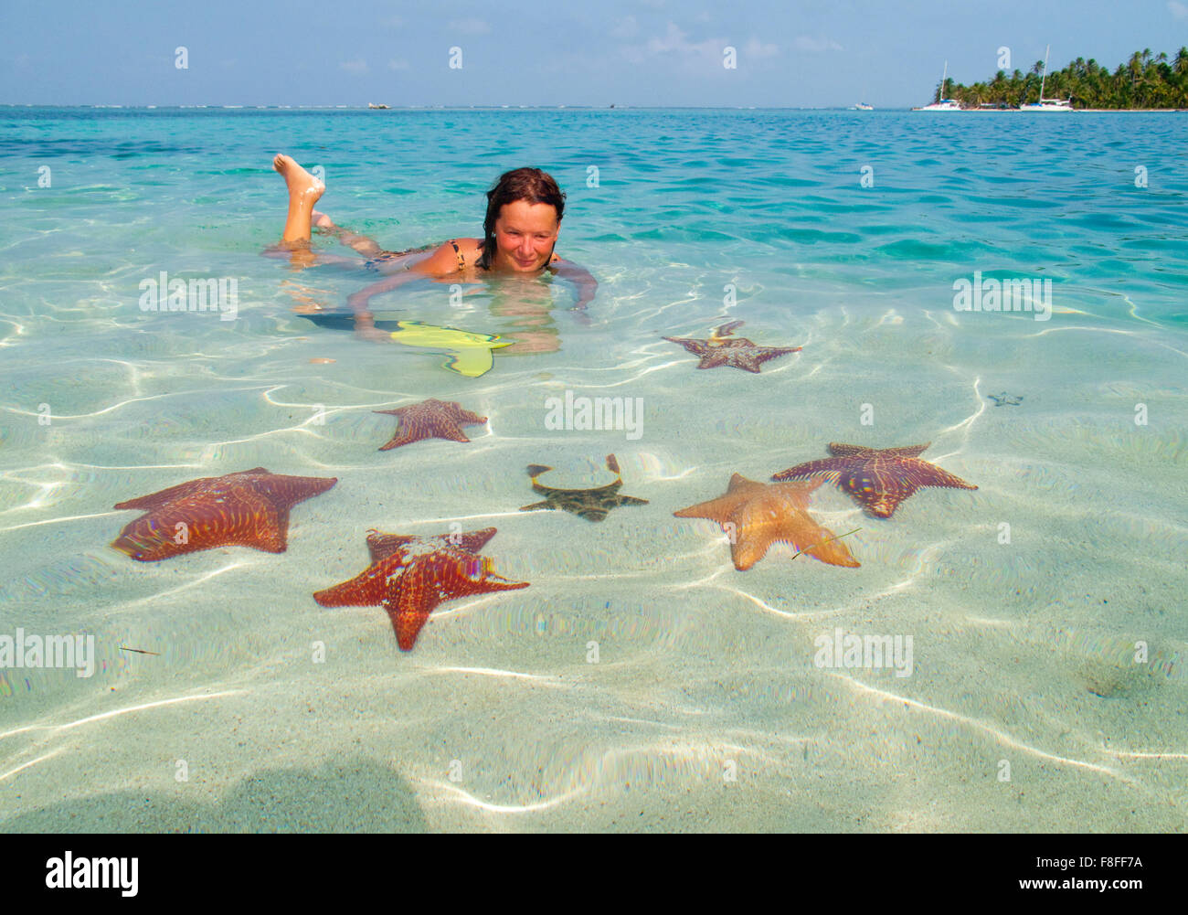 girl in caribean waters, surrounded by starfishs Stock Photo