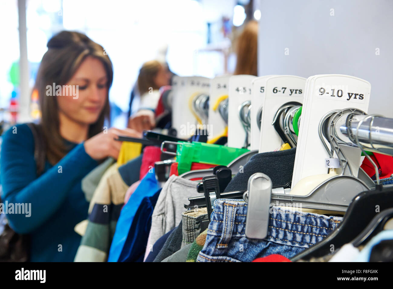 Woman Buying Children's Clothes In Charity Shop Stock Photo Alamy