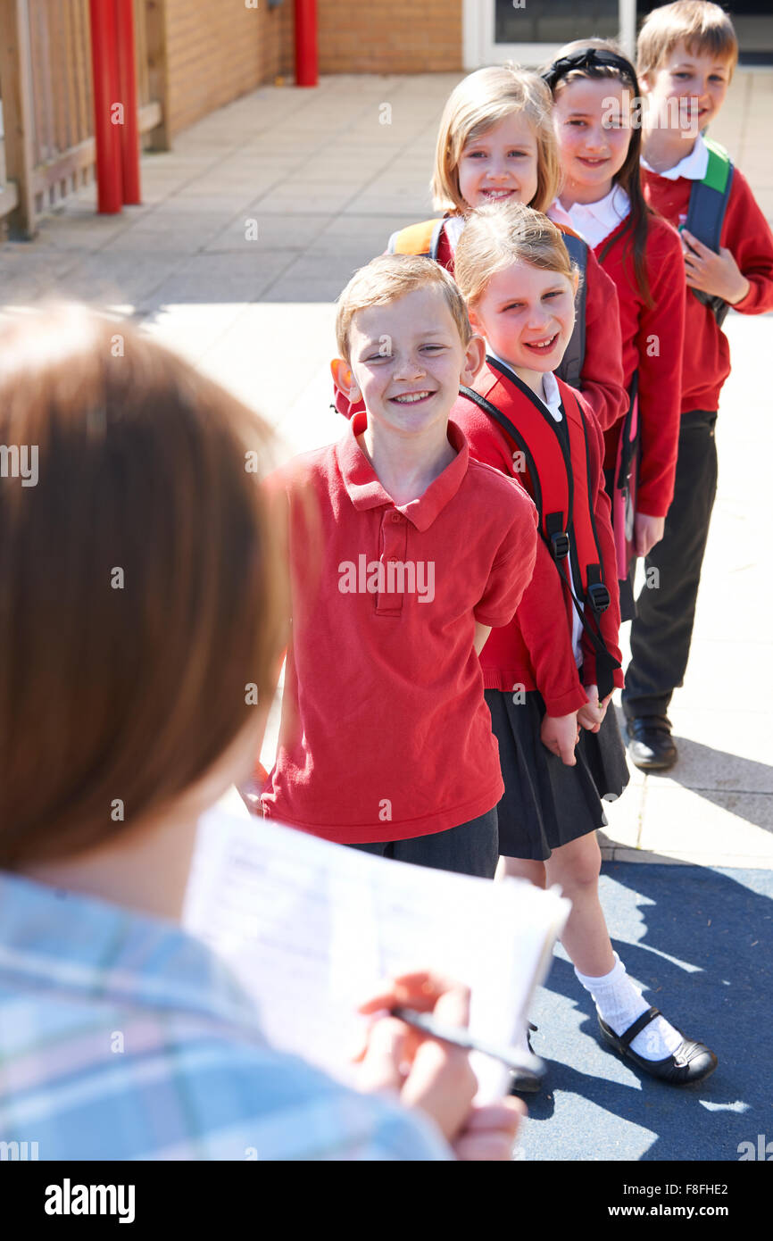 Teacher Taking School Register In Playground Stock Photo