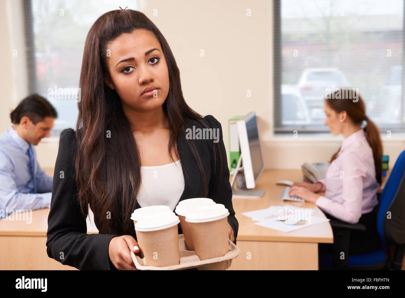 Fed Up Female Intern Fetching Coffee In Office Stock Photo